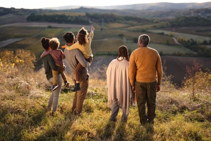 Multi-generation family standing together overlooking countryside landscape.
